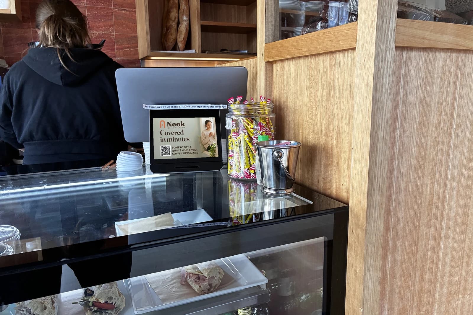 A full-screen health-insurance ad on the customer screen at a neighbourhood café counter.