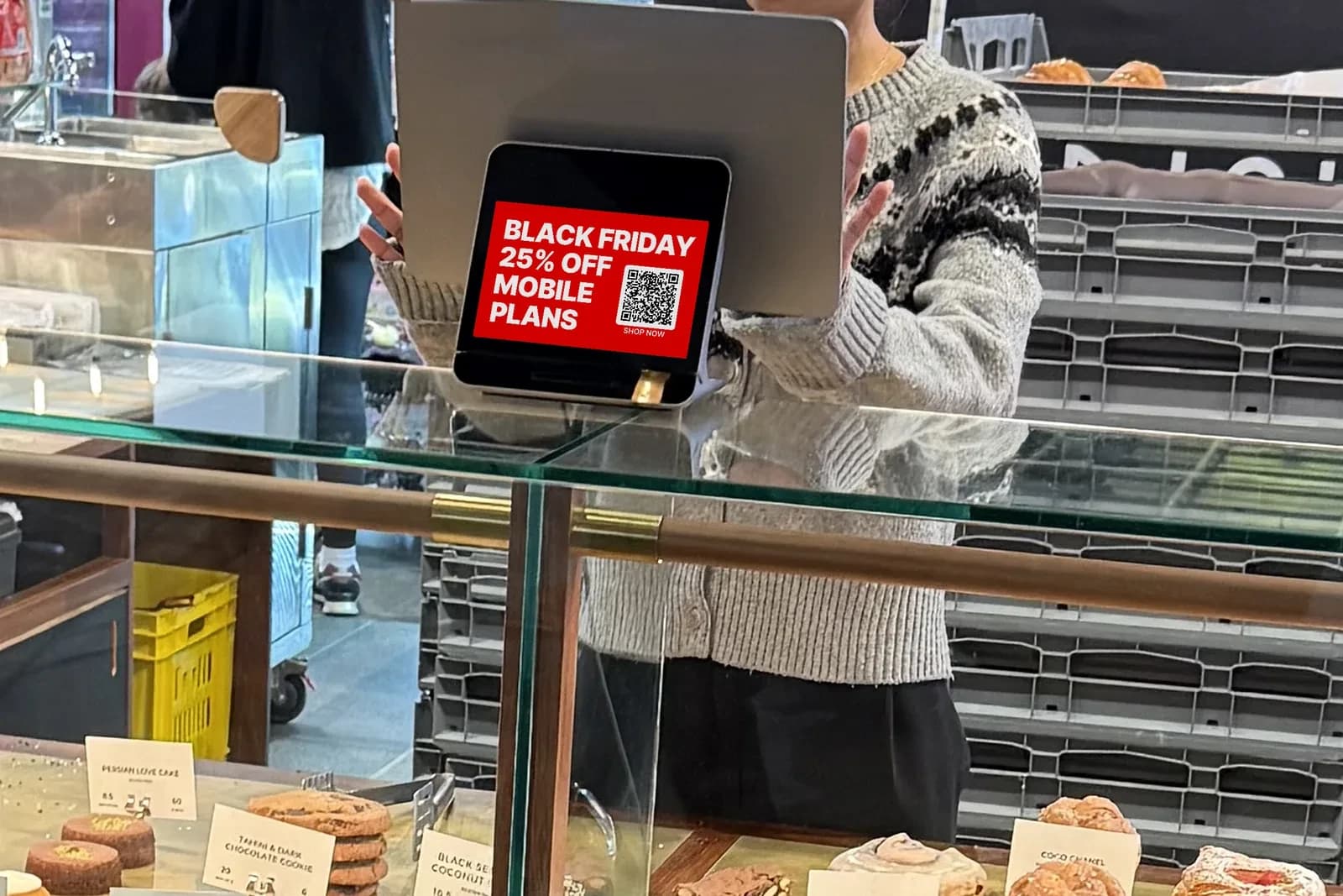 A full-screen Black Friday mobile-plans ad on the customer screen at a bakery counter.